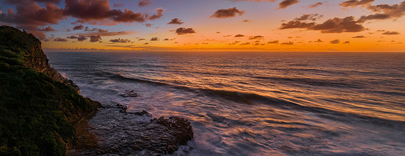 Surfs up sunrise at the seaside with scattered clouds