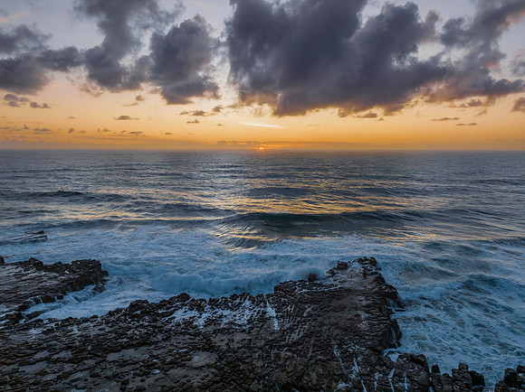 Surfs up sunrise at the seaside with scattered clouds