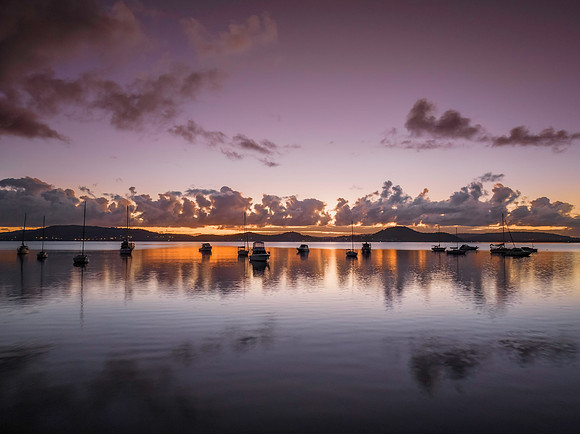 Aerial sunrise waterscape with boats, clouds and reflections