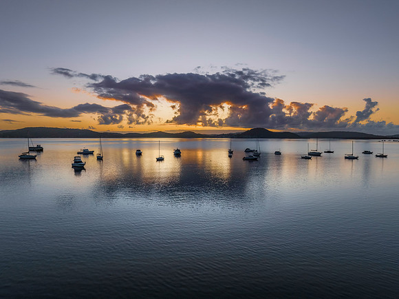 Aerial sunrise waterscape with boats, clouds and reflections