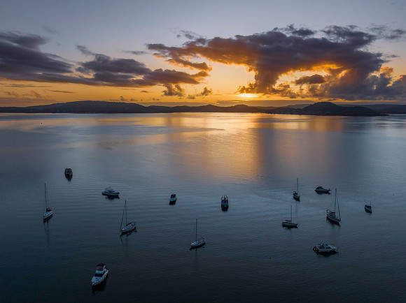 Aerial sunrise waterscape with boats, clouds and reflections