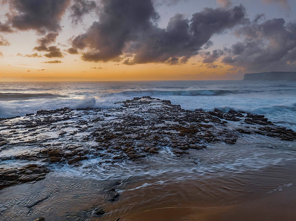 Surfs up sunrise at the seaside with scattered clouds