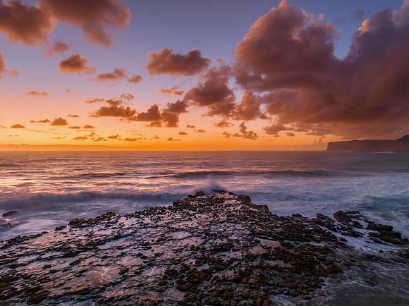 Surfs up sunrise at the seaside with scattered clouds