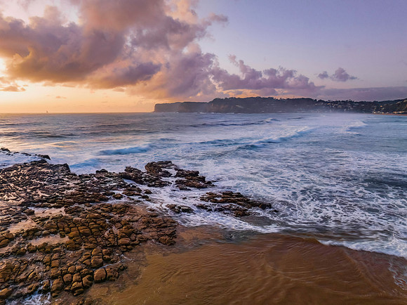 Surfs up sunrise at the seaside with scattered clouds
