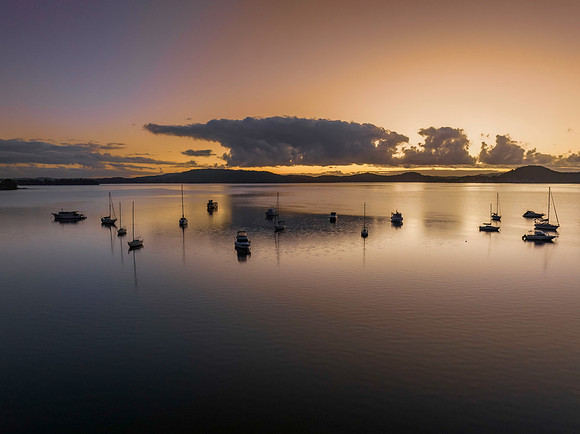 Aerial sunrise waterscape with boats, clouds and reflections