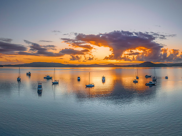 Aerial sunrise waterscape with boats, clouds and reflections