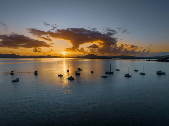 Aerial sunrise waterscape with boats, clouds and sun rays