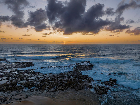 Surfs up sunrise at the seaside with scattered clouds