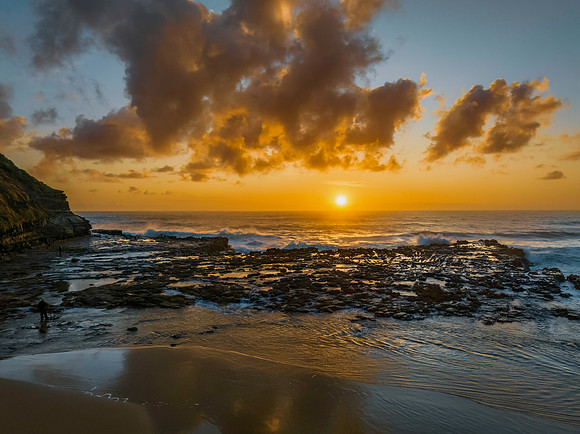 Surfs up sunrise at the seaside with scattered clouds