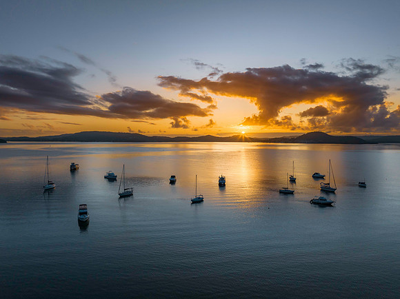 Aerial sunrise waterscape with boats, clouds and sun rays