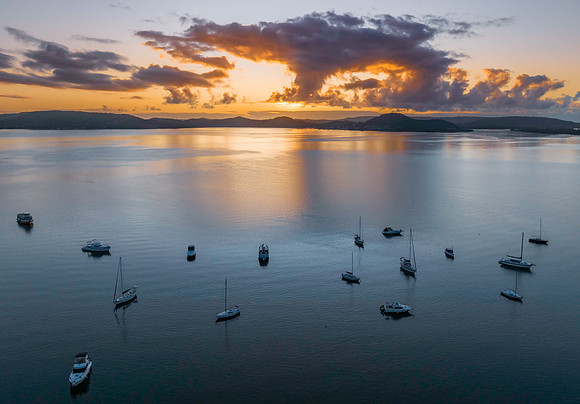 Aerial sunrise waterscape with boats, clouds and reflections
