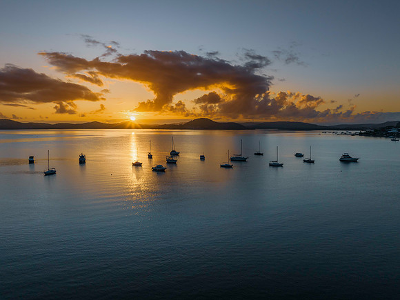 Aerial sunrise waterscape with boats, clouds and sun rays