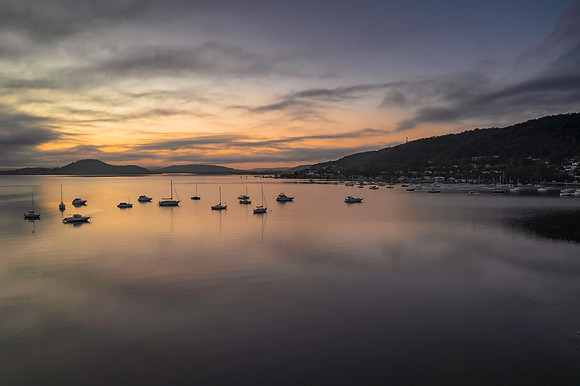 Sunrise waterscape with boats, soft clouds and reflections