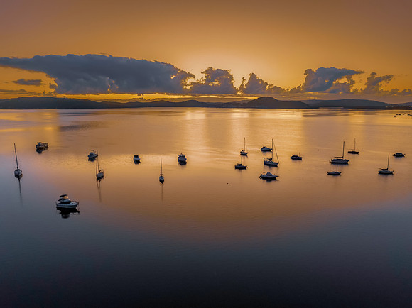 Aerial sunrise waterscape with boats, clouds and reflections