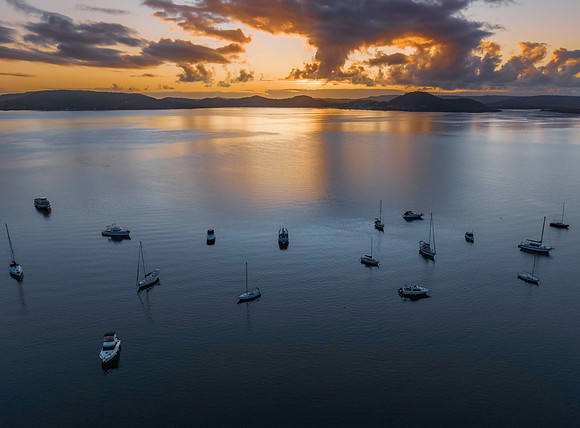 Aerial sunrise waterscape with boats, clouds and reflections