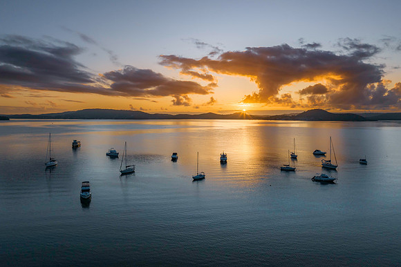 Aerial sunrise waterscape with boats, clouds and sun rays