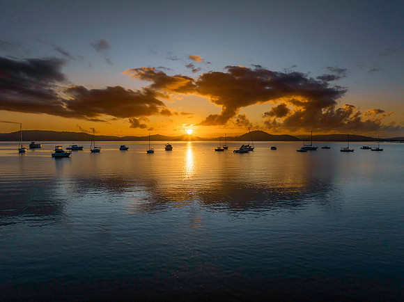 Aerial sunrise waterscape with boats, clouds and the sun