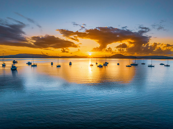 Aerial sunrise waterscape with boats, clouds and sun rays