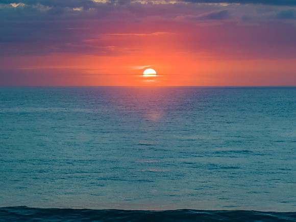 Beautiful colourful sunrise with sun and clouds over the ocean