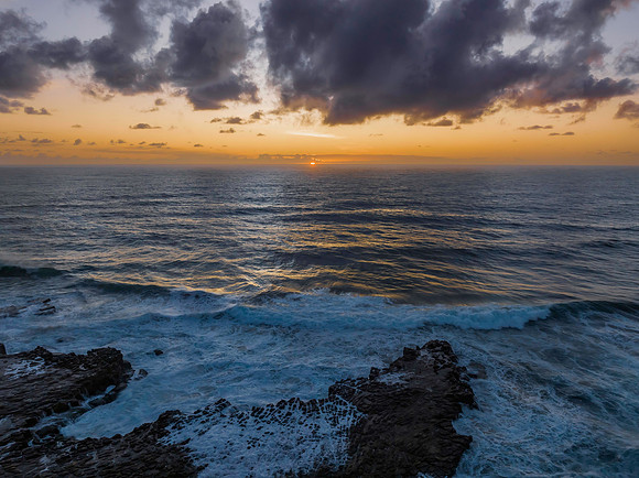 Surfs up sunrise at the seaside with scattered clouds