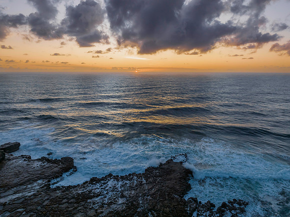 Surfs up sunrise at the seaside with scattered clouds