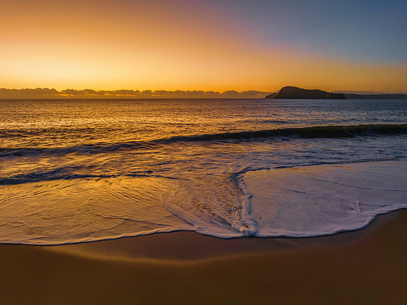 Aerial sunrise seascape with clear skies and low cloud bank