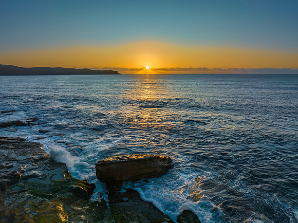 Aerial sunrise seascape with clear skies and sunrays