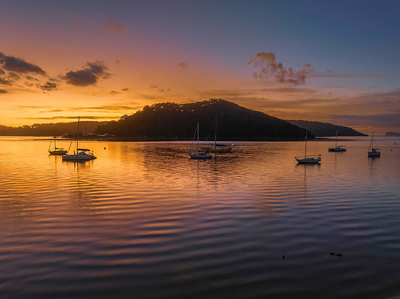 Aerial sunrise waterscape with boats and scattered clouds