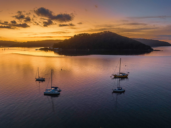 Aerial sunrise waterscape with boats and scattered clouds
