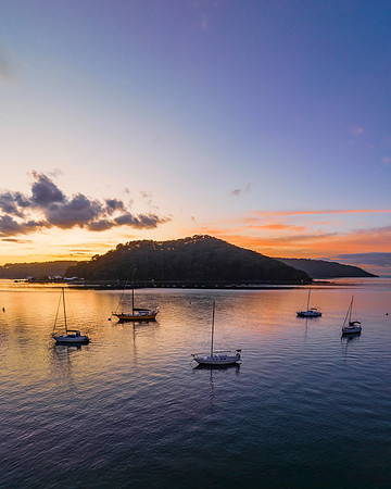 Aerial sunrise waterscape with boats and scattered clouds