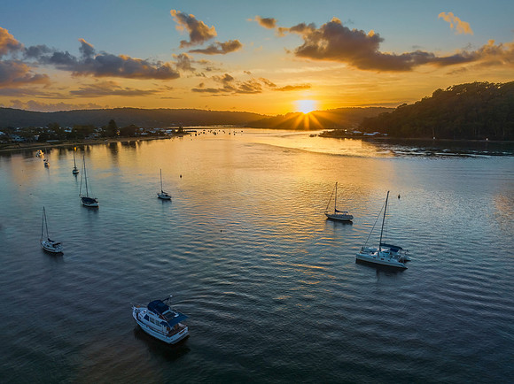 Aerial sunrise waterscape with boats and scattered clouds