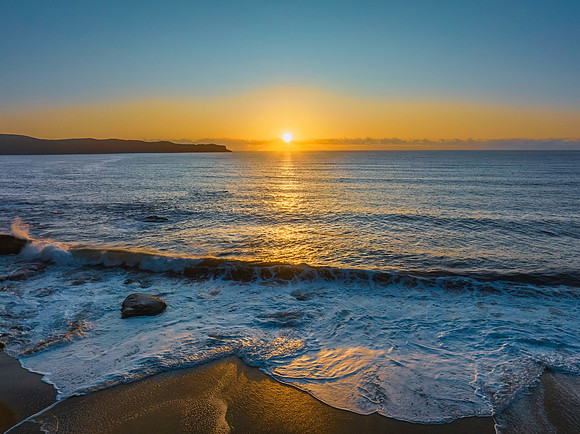 Aerial sunrise seascape with clear skies and sun above the horiz