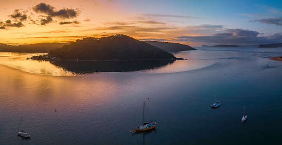 Aerial sunrise waterscape with boats and scattered clouds