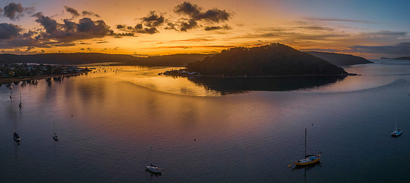 Aerial sunrise waterscape with boats and scattered clouds