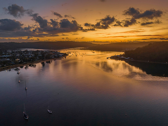 Aerial sunrise waterscape with boats and scattered clouds