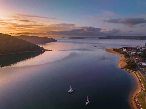 Aerial sunrise waterscape with boats and scattered clouds