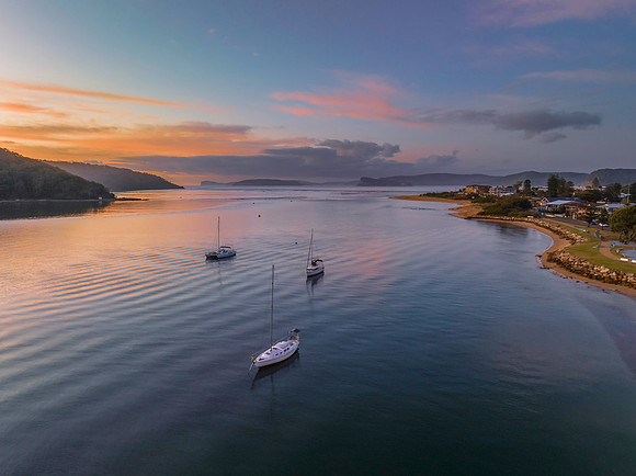 Aerial sunrise waterscape with boats and scattered clouds