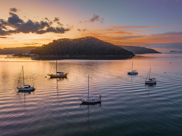 Aerial sunrise waterscape with boats and scattered clouds
