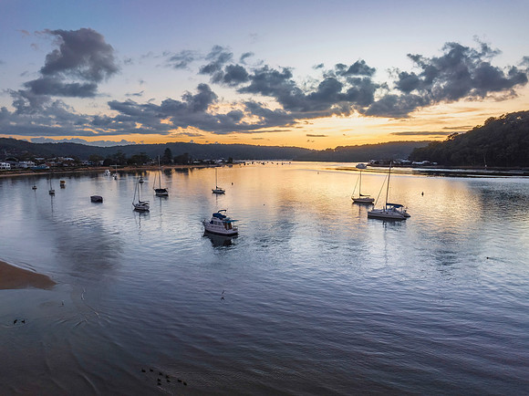 Aerial sunrise waterscape with boats and scattered clouds