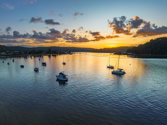 Aerial sunrise waterscape with boats and scattered clouds