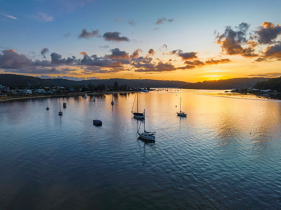 Aerial sunrise waterscape with boats and scattered clouds