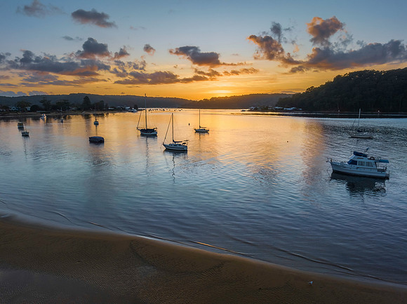 Aerial sunrise waterscape with boats and scattered clouds