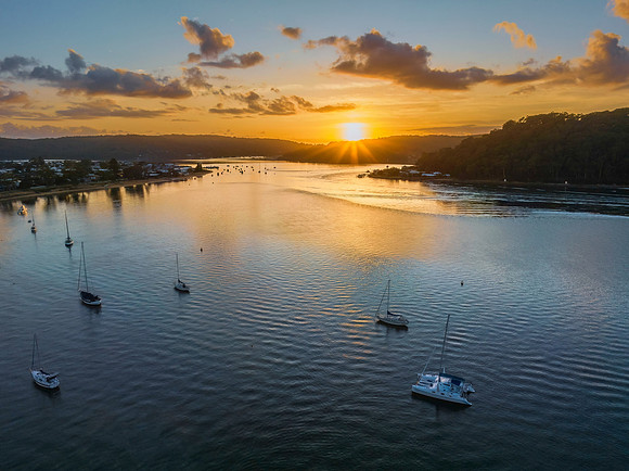 Aerial sunrise waterscape with boats and scattered clouds