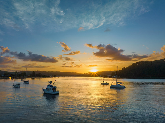Aerial sunrise waterscape with boats and scattered clouds