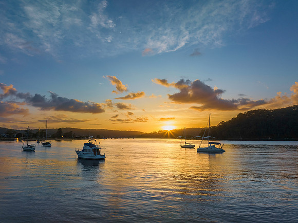 Aerial sunrise waterscape with boats and scattered clouds