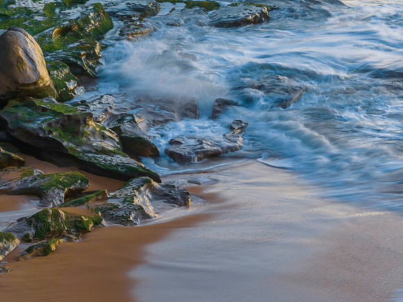 Sunrise at the seaside with waves breaking on the rocks