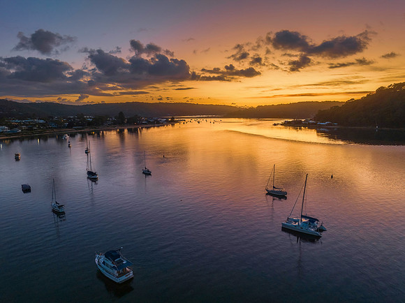 Aerial sunrise waterscape with boats and scattered clouds