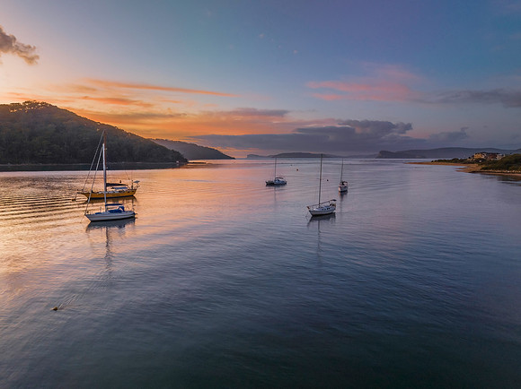Aerial sunrise waterscape with boats and scattered clouds