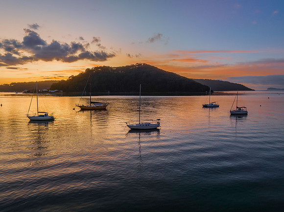 Aerial sunrise waterscape with boats and scattered clouds
