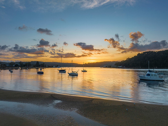 Aerial sunrise waterscape with boats and scattered clouds